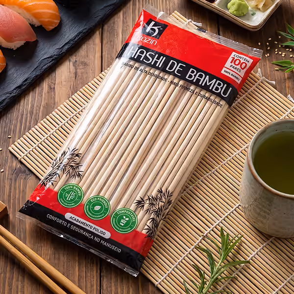 Pacote de hashi de bambu Kozin com 100 pares sobre esteira de bambu, ao lado de sushis e de uma xícara de chá verde