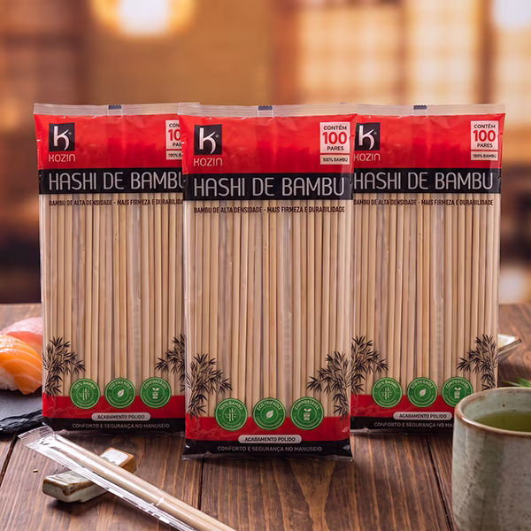 Três pacotes de hashi de bambu Kozin com 100 pares, em pé sobre mesa de madeira com sushis e chá verde
